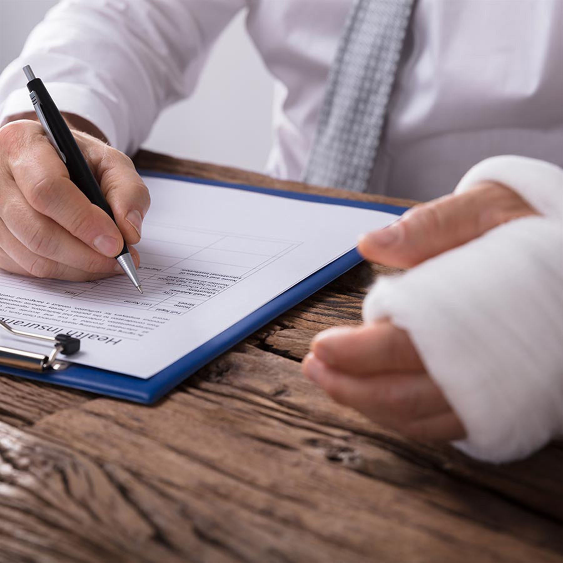Man with cast writing on clipboard